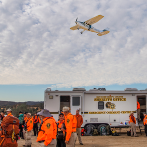 Aero Squadron Plane Flying Above Search and Rescue Volunteers